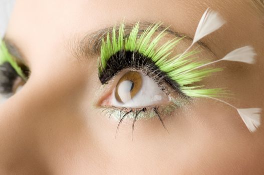detail of an eye with green artificial eyelashes