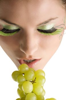 close up of a young girl and beautiful girl with grape near her mouth