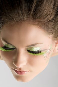 particular point of view of a face of a young brunette with green eyelashes