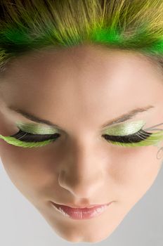 close up of a face of a girl with green eyelashes and yellow green hair
