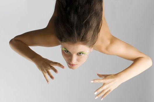 cute brunette with green eyelashes in act to be agressive moving hand like claw