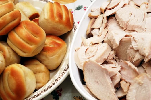 Holiday dinner with sliced turkey and rolls.