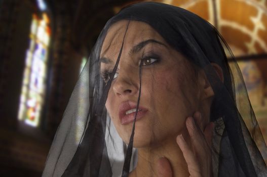 cute woman like widow with a black transparent veil on her face in church