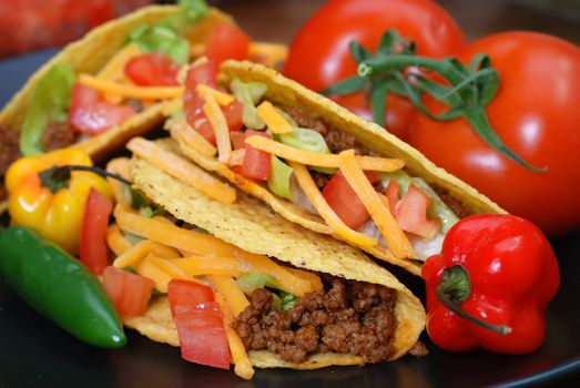 Closeup of tacos on plate with tomatoes, habanero and serano peppers.