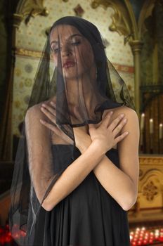 very cute widow in black dress and veil on face inside a church