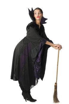 nice witch in black taking pose using a broom as a walking stick