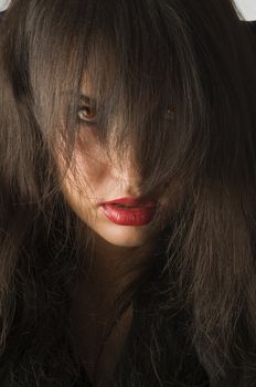 woman with black hair on face and red eyes looking anger in camera