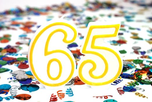 Number 65 celebration candle with confetti.
