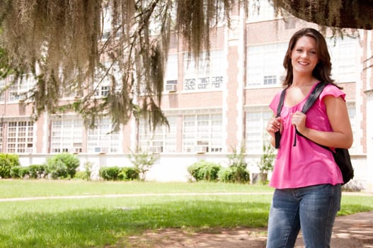 Female college student standing in front of school with backpack.  