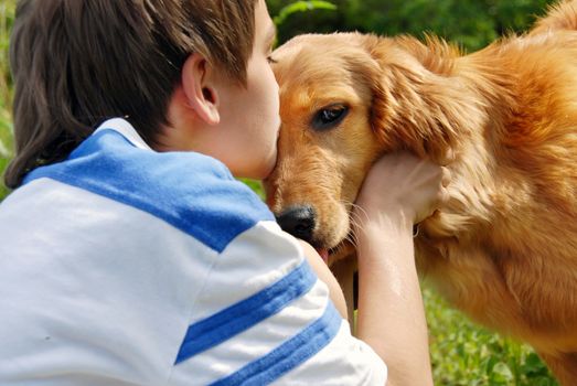 little boy kissing golden retriever dog closeup