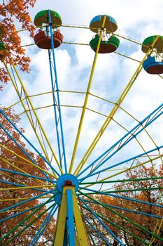 Old big wheel in autumn park against the blue cloudy sky