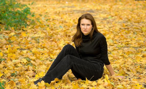 The sad young girl in autumn park during a leaf fall
