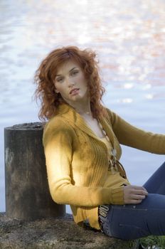 romantic outdoor autumn portrait near a river of a red-haired woman