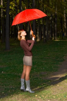 The young girl with a red umbrella in autumn park