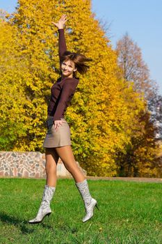 The nice jumping girl against the autumn nature
