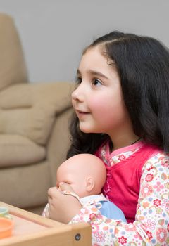 adorable little brunette girl playing with doll