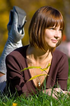 The young girl on green grass in autumn park