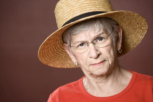 Senior woman in a red shirt and straw hat