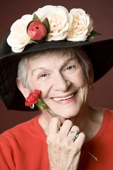 Senior woman in a red shirt and hat with flowers