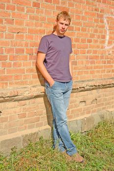 Young stylish man with blonde hair stand near brick wall.