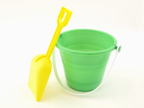 A green plastic bucket and yellow shovel isolated on a white background