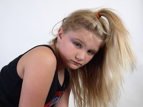 Young blonde girl with a blonde pony tail and a sad or serious look on her face. Over white.