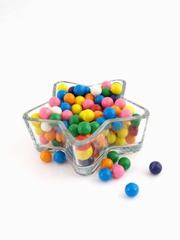 A star shaped dish filled with multi colored gumballs isolated over a white background.