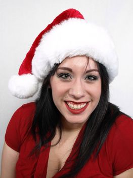 A pretty young pierced adult woman in a Santa hat cheerfully smiles.