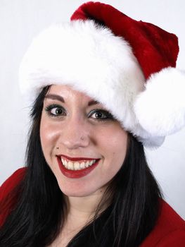 A pretty young pierced adult woman in a Santa hat cheerfully smiles.