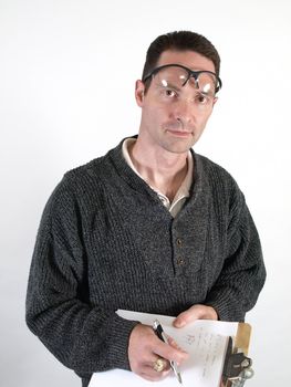 A man with safety glasses pushed up on his forehead, writes a few notes on a clipboard.