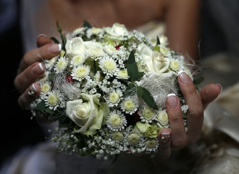 Wedding bouquet from roses and chrysanthemums on a background of a dress