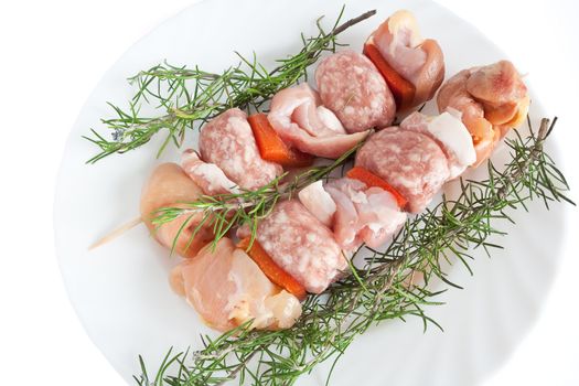 raw pork kebab on a plate with rosemary isolated on white background with clipping path