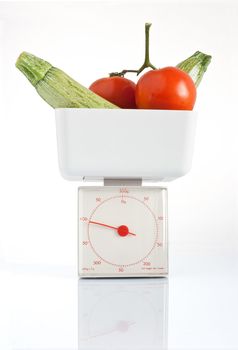 vegetables on kitchen scale isolated on white background with clipping path