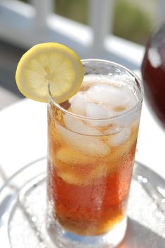 Glass on iced tea with lemon slice garnish on table.