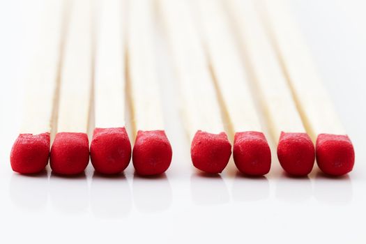 closeup of some red match heads on white background