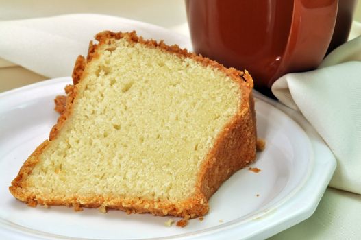 Closeup of pound cake with napkin and cup of coffee in background.