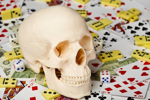 The skull on a background of playing cards, dominoes and money
