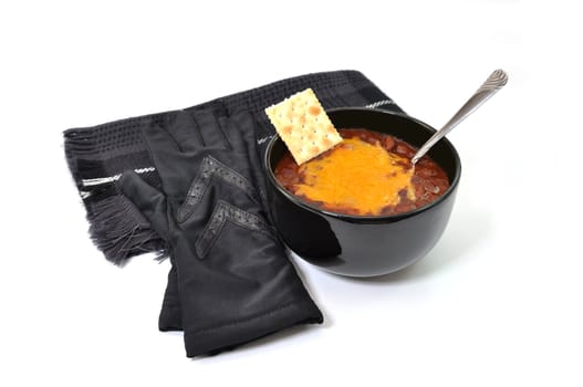 Bowl of chili with melted cheese and spoon and gloves and scarf.  Isolated on white background.