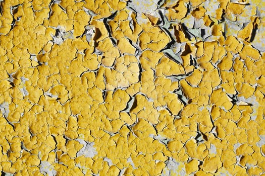 The texture of the old walls covered with peeling yellow paint