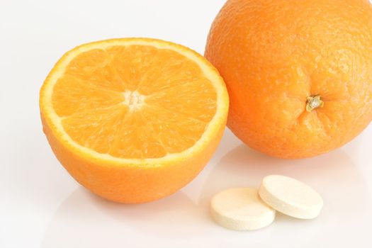 Large pills with orange fruits tube on bright background
