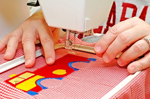 Woman operating embroidery machine.