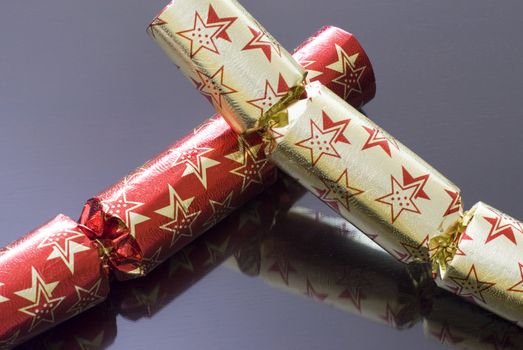 a couple of christmas crackers on a reflective surface