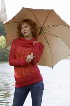 cute red haired girl near river with umbrella and red pullover