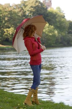 very cute girl looking river with colored umbrella and red pullover