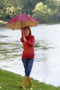 very nice girl closing her umbrella in park near a river