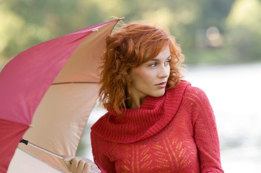 beautiful outdoor shot of woman in red with umbrella on green background
