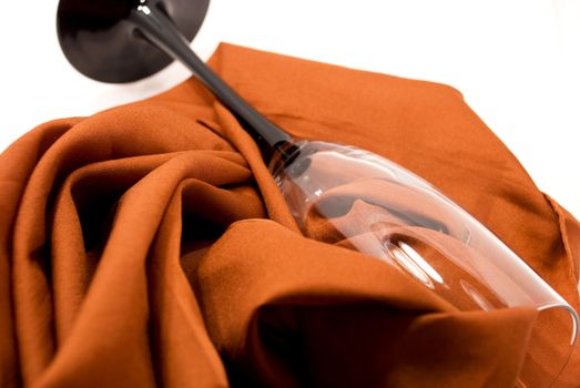 Tall wine glass lying on table, on fabrics in pleat,on white background
