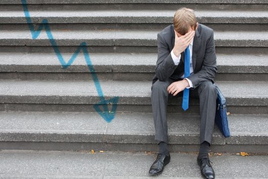 A worried business man sitting on some stairs