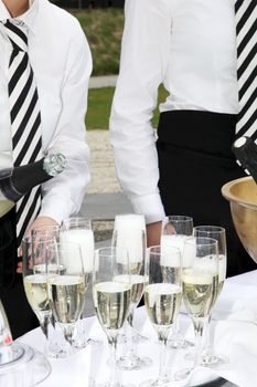 Two waiters fill glasses of champagne at a party.