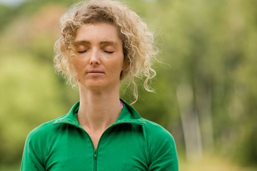 Portrait Of A Mature Blond Woman Meditating In Nature